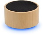 5 x 4 cm. Parlante Bluetooth. Caja redonda de Bambú color natural con malla metálica en la parte superior. Base negra con panel de control. Permite recibir llamadas. Micrófono incorporado. Versión bluetooth: 5.0. Batería: 300 mAh. Potencia: 3W. Cable de carga y conexión USB tipo C en color negro. Presentación en caja de regalo Kraft.